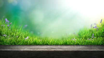 A wooden table product display with summer garden background of green grass and blurred foliage with strong sunlight.