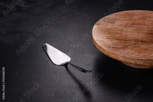 A metal cake blade with an empty brown cake stand on a dark concrete background photo