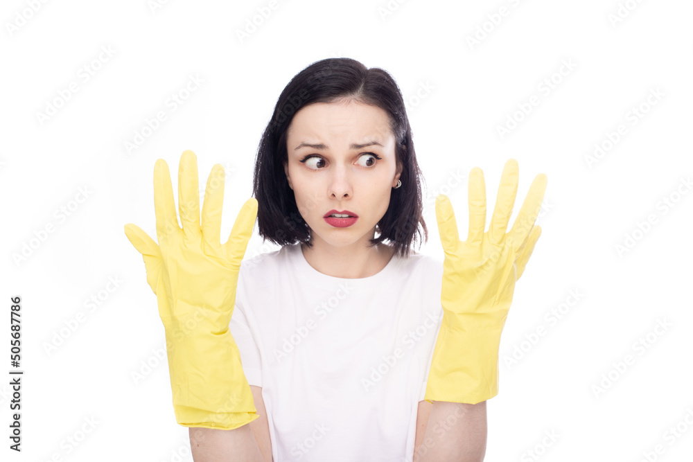 brunette woman in fear looks at her hands in gloves for washing dishes