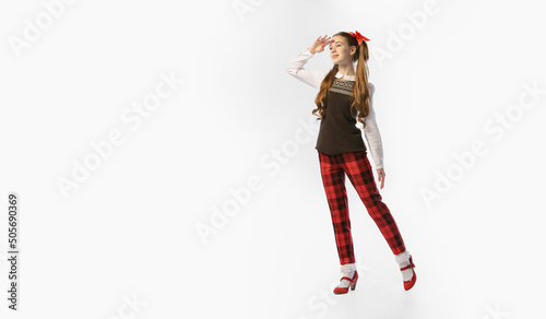 One young beautiful smiling girl, teenager in retro style outfit, fashion of 70s, 80s years standing isolated on white studio background with copyspace for ad.