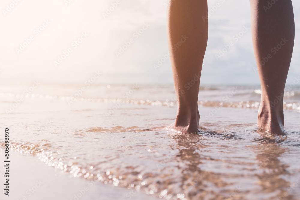 Close up woman legs walking on tropical sunset beach with smooth wave and bokeh sun light wave abstract background. Travel vacation and freedom feel good concept. - obrazy, fototapety, plakaty 