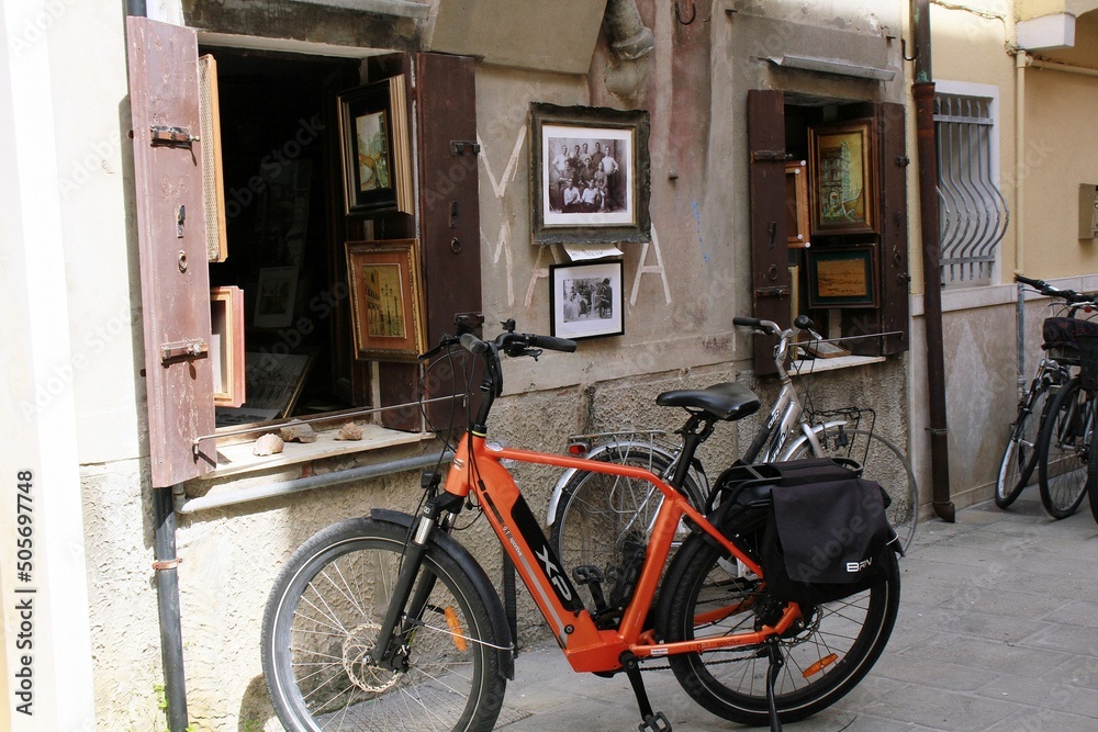 Bicicletas aparcadas frente a fachada antigua de exhibición de pinturas y fotos.