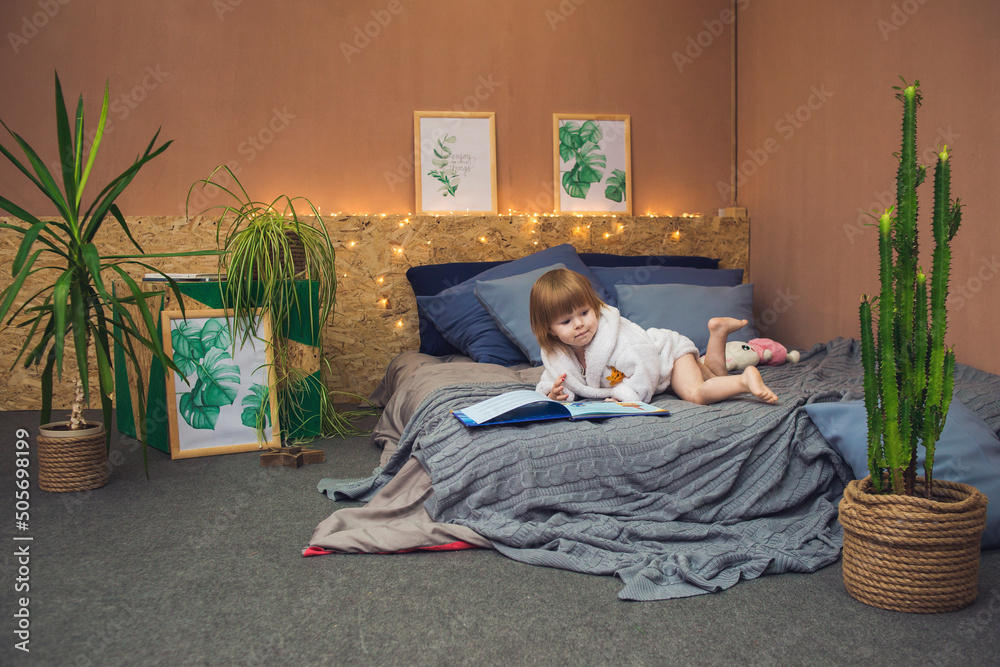 beautiful cute little girl in a white terry bathrobe on the bed. happy child playing - obrazy, fototapety, plakaty 