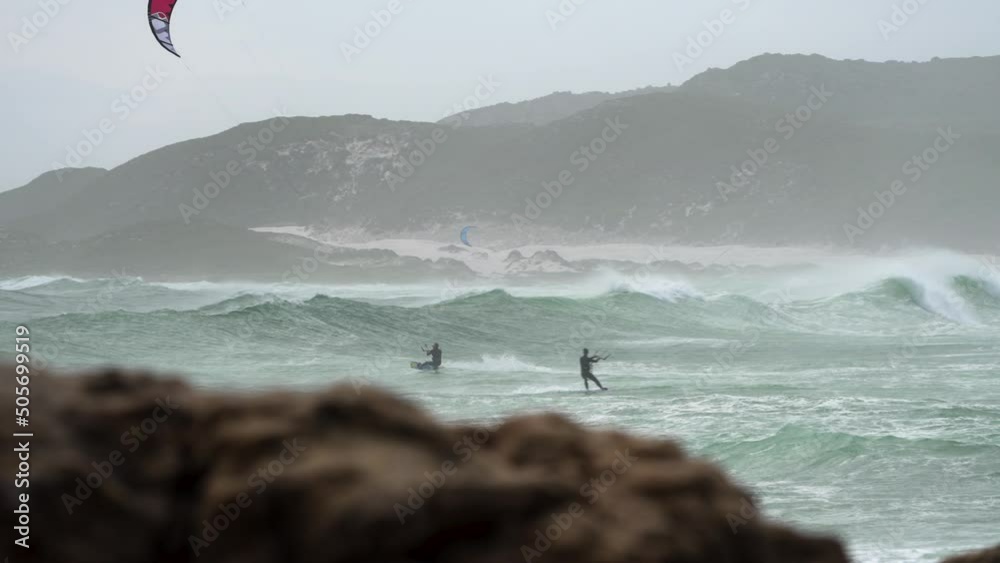 Kitesurfer on board flying off stormy wave performing big kiteloop in Cape Point