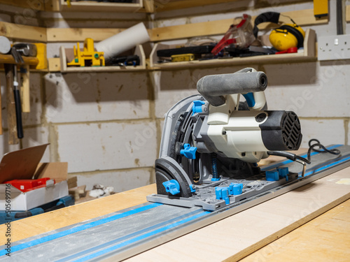 Electric motor track saw on a length of aluminium track ready to cut a length of wooden board