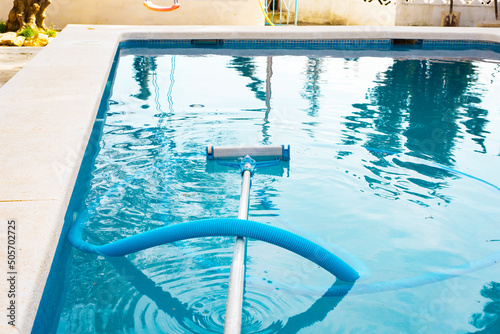 a swimming pool without people with a hose and a mop a vacuum cleaner for cleaning the pool water.preparing and cleaning the pool for the swimming area