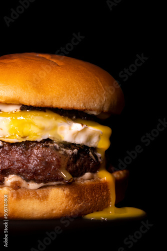 hamburguesa con queso de cabra y huevo sobre fondo negro