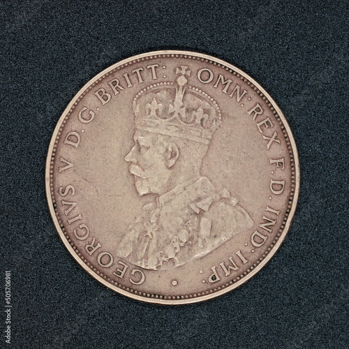 Obverse side of an Australian one penny coin coin from 1932, made of bronze and featuring King George V, on a black surface