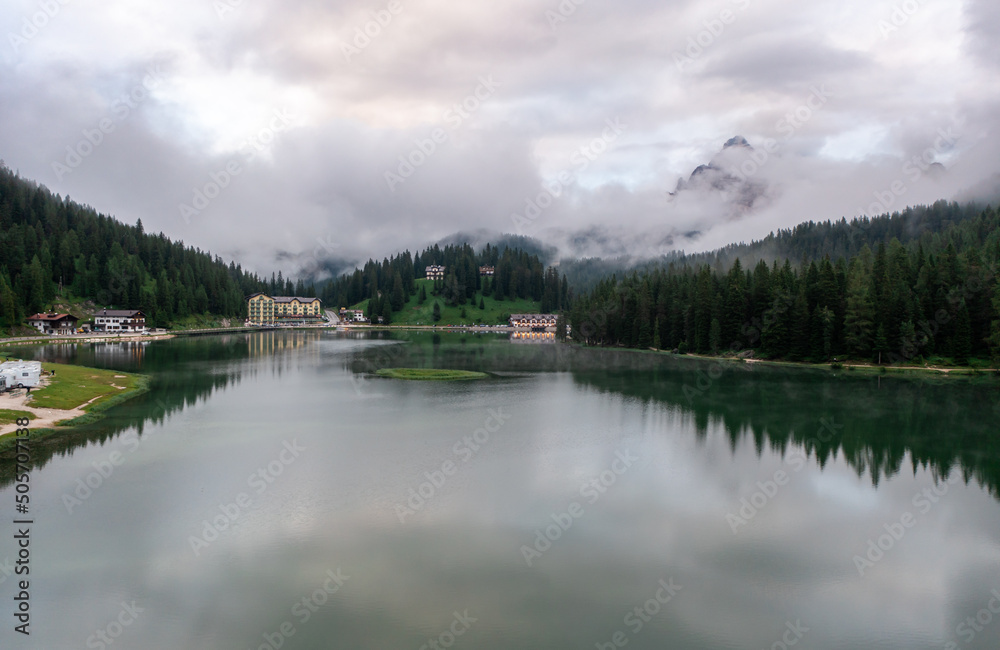 Panorama drone view of Lago di Misurina, reflection of the mountain in the lake, flying through the fog in the Dolomites in Italy