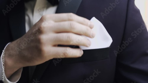 the groom adjusts the handkerchief in the breast pocket of his jacket