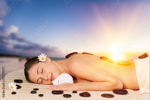Beauty and relaxation concept - beautiful young woman on massage at spa over tropical beach background.