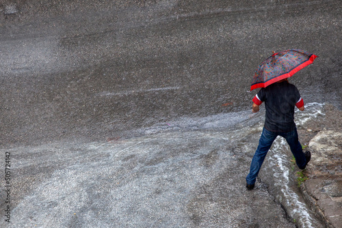 unrecognizable man holding umbrella ,crossing the road while heavy rain 