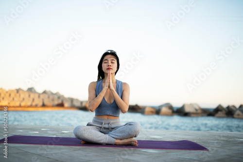 Beautiful young woman training outside. Fit woman doing yoga exercise.