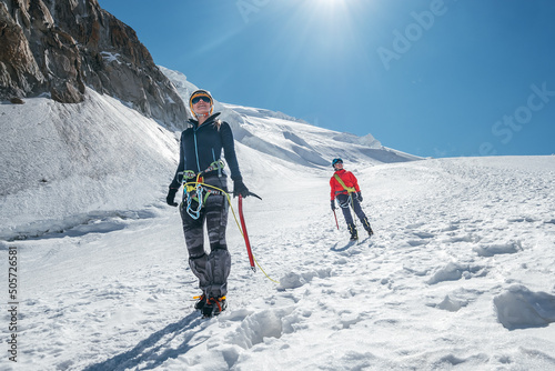 Fotografering Two laughing young women Rope team descending Mont blanc du Tacul summit 4248m dressed mountaineering clothes with ice axes walking by snowy slopes