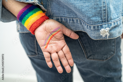Asian lady wearing rainbow flag wristbands, symbol of LGBT pride month celebrate annual in June social of gay, lesbian, bisexual, transgender, human rights. © amazing studio