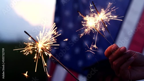 Happy 4th of July Independence Day, Hand holding Sparkler fireworks USA celebration with American flag background. Concept of Fourth of July, Independence Day, Fireworks, Sparkler, Memorial, Veterans