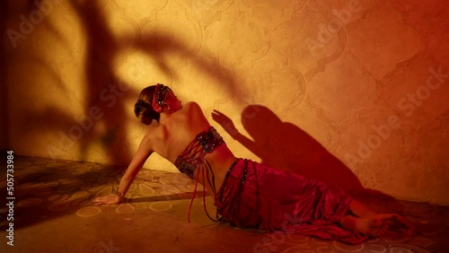 tempting concubine in harem is dancing oriental dance, lying on floor and moving seductively photo