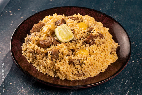 Spicy beef biryani in plate with lemon on marble background top view of indian and pakistani food photo