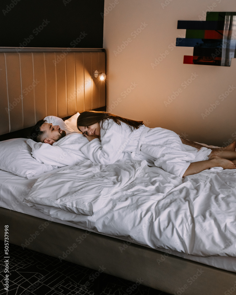 European couple hugging together while lying in bed at hotel