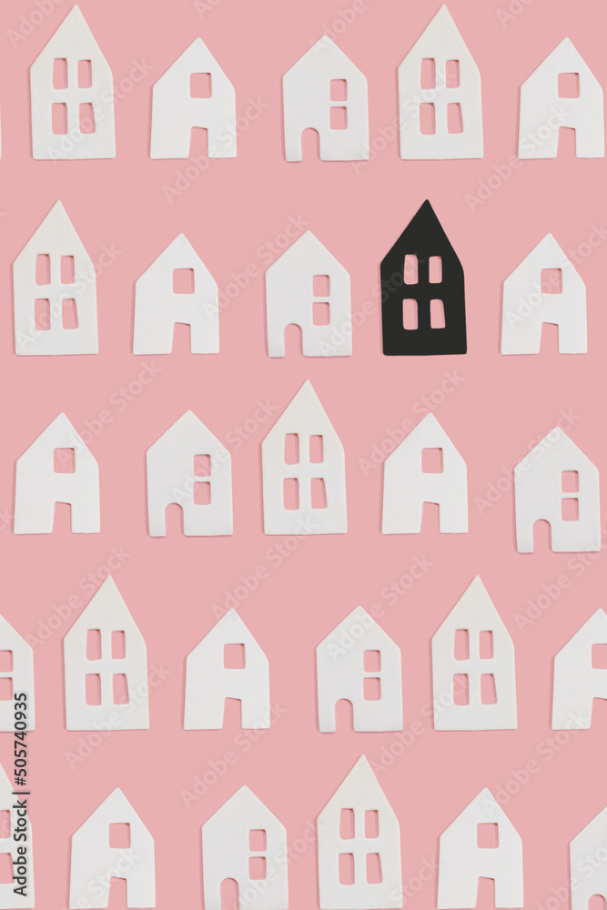 White and one black small decor ceramic houses with windows on pink flat lay background. Minimal creative card or wallpaper idea. Top view pattern. Stand out concept.