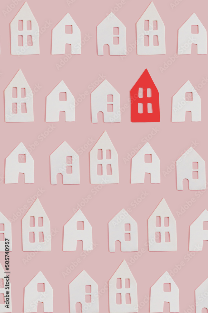 White and one red small decor ceramic houses with windows on pink flat lay background. Minimal creative card or wallpaper idea. Top view pattern. Stand out concept.