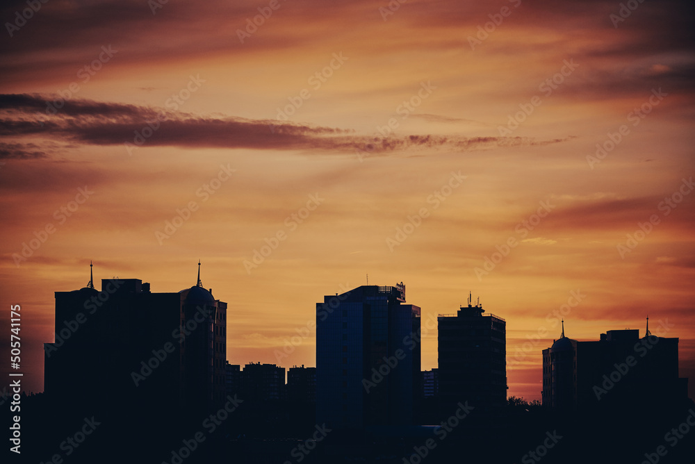 Silhouette of city buildings against the sky during sunset.