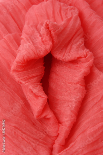 Soft folds of pink fabric in the shape of vagina. Textile abstract background. Sexy concept. Closeup. Selective focus.