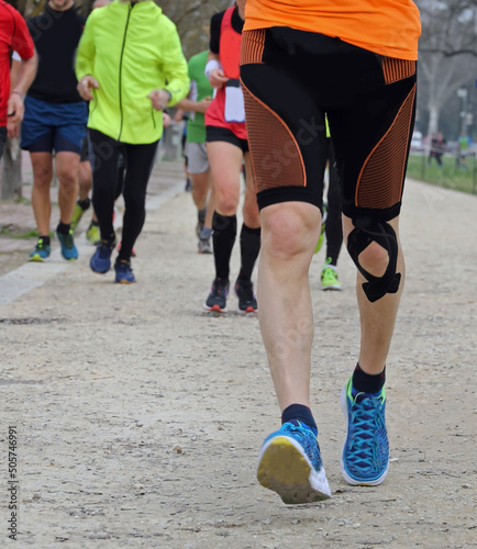 Young marathoner runs with athletic taping on the his knee during the race