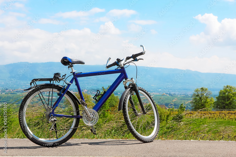 Mountain bicycle on a country road on the background of mountains and meadows in Switzerland.