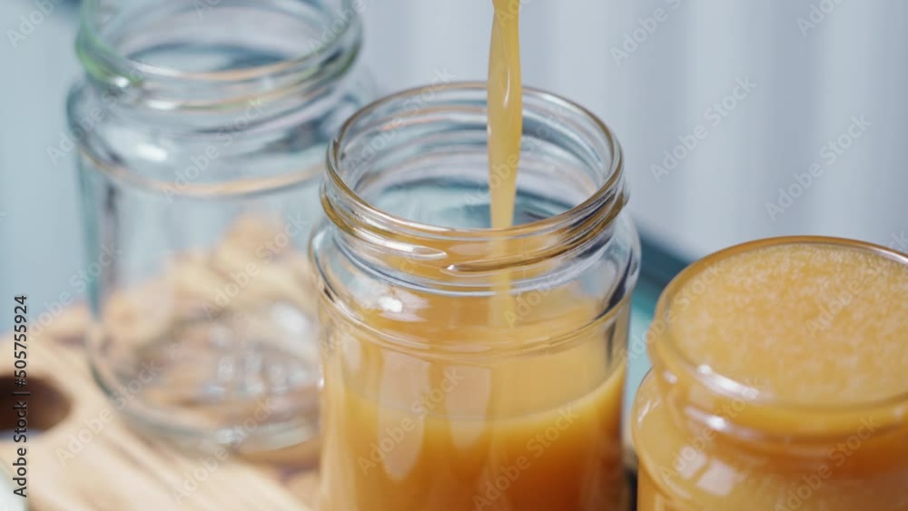 liquid homemade caramel pours in a thin stream into a jar liquid homemade caramel pours in a thin stream into a jar