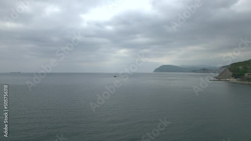 4K. Blue water with small waves turned black in cloudy weather. Clouds from the height of the drone are moving forward. On the horizon, you can see how the sun's rays are breaking through. photo