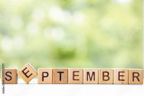 The word September on wooden cubes. They lie on other cubes against the backdrop of the summer garden. Month of year photo