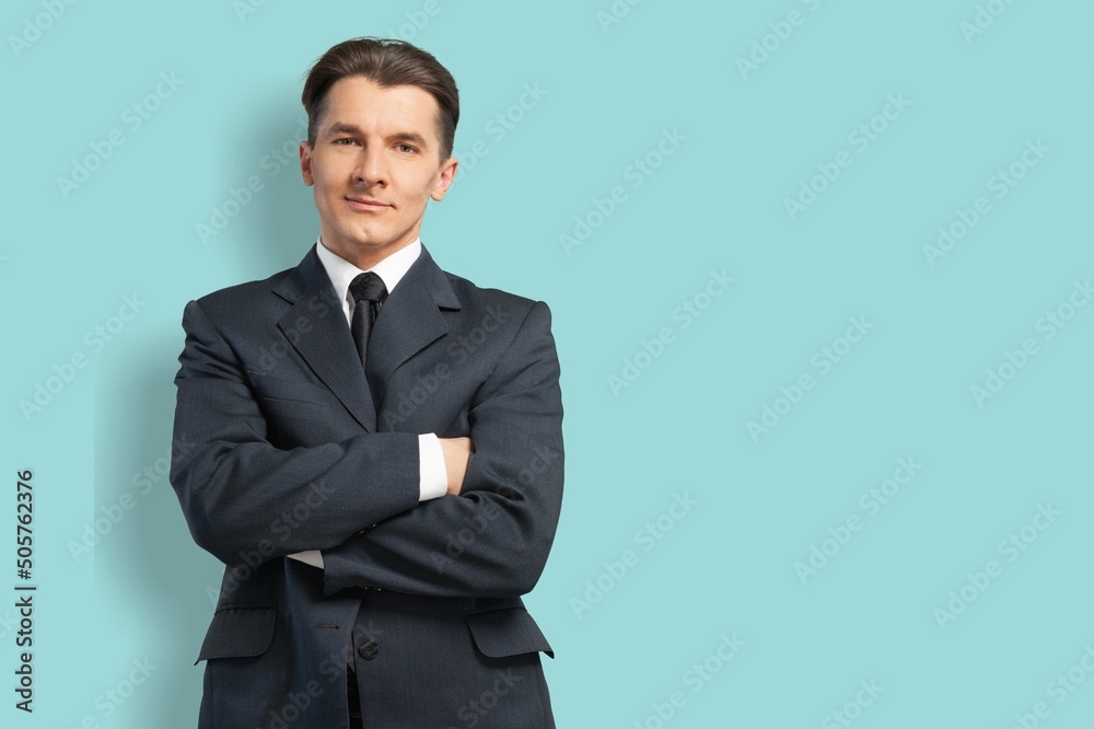Smiling young businessman in black suit on pastel background Smiling young businessman in black suit on pastel background