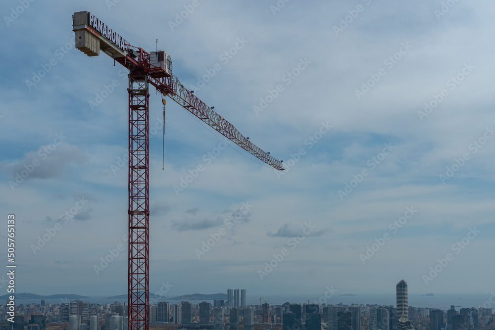 A high-rise construction crane towers over the city with high-rise buildings and skyscrapers in Istanbul, the sea and islands in the background, Turkey photo