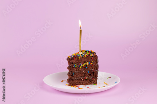 Birthday party background. Chocolate cake with golden candles on pick background.