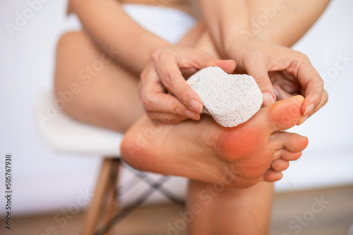 Woman cleans the heel of the foot with pumice at home photo