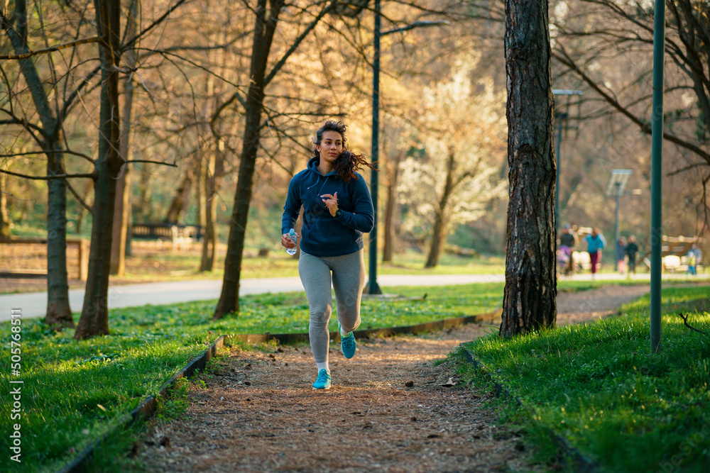 A beautiful curvy woman runs in a nature park at sunset.