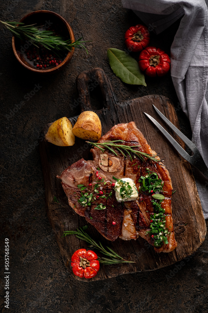 Φωτογραφία Porterhouse roast steak or Florentine beef steak with butter on a cutting board with seasonings and vegetables