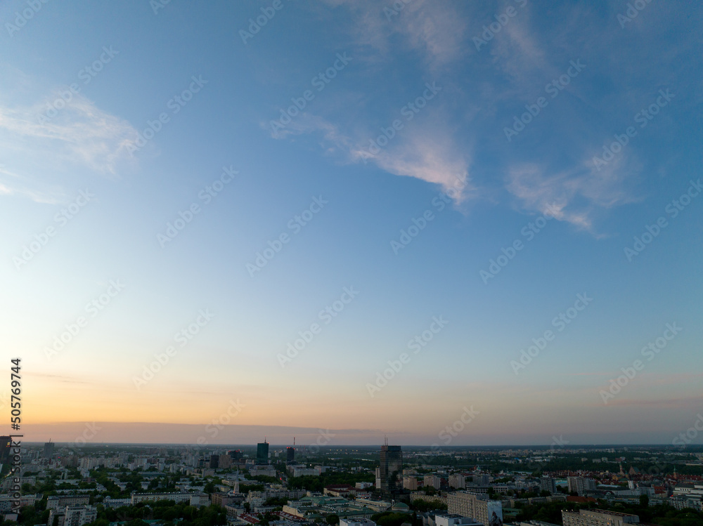 Centrum Warszawy, widok na bloki, wieżowce mieszkalne i biurowce, panorama z lotu ptaka z drona, zachód słońca, wiosna, zielone drzewa, niebieskie niebo