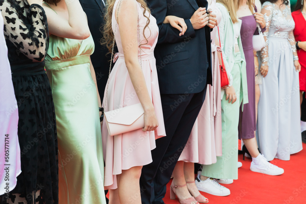 Prom guests standing on a red carpet, close up