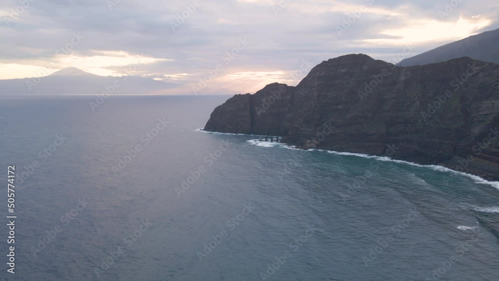 Aerial view of cliffs in Hermigua, La Gomera, Canary Islands. Incredible View from the island of La Gomera to the island of Tenerife at sunrise. The snow-capped peak of the Teide volcano can be seen i Aerial view of cliffs in Hermigua, La Gomera, Canary Islands. Incredible View from the island of La Gomera to the island of Tenerife at sunrise. The snow-capped peak of the Teide volcano can be seen i