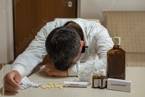 Image of a man sleeping with his head resting on the table after abusing alcohol, anxiolytics and antidepressants. photo