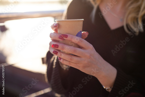 girl drinking coffee on the street from a paper cup
