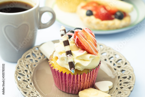 Obraz na płótnie Whipped cream cupcake decorated with fruits, chocolate and gold sprinkles on romantic plate. Dessert and coffee in heart shaped ornament and other pastry. w salonie