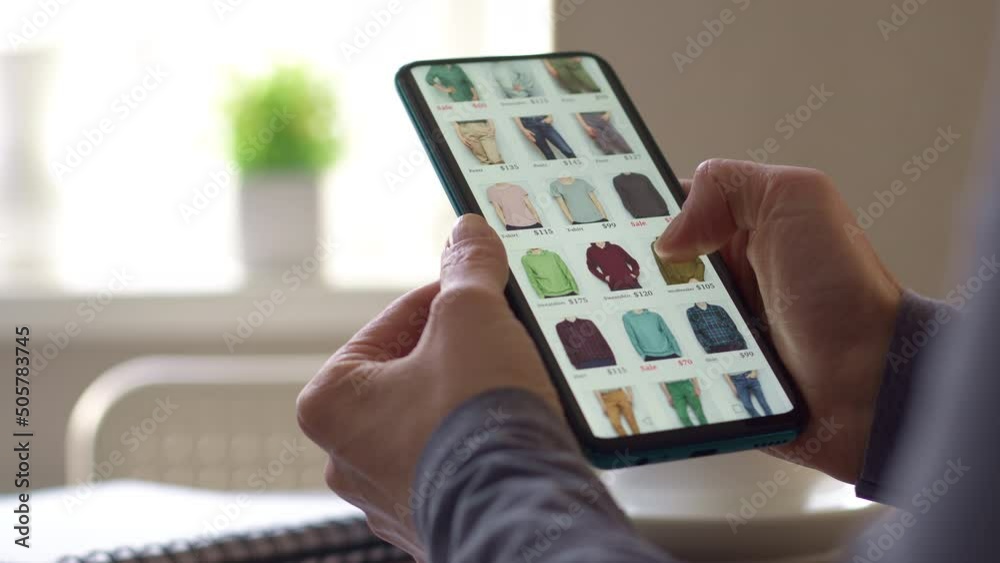 Buying clothes in the online store using the application in the smartphone. A woman looks at a product on a phone screen. E-commerce concept.