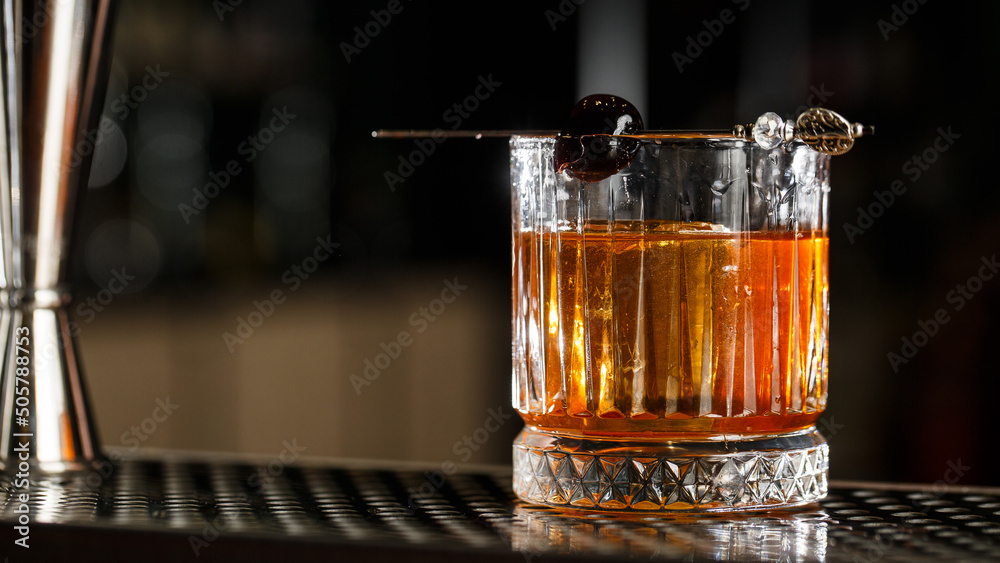 Old fashioned cocktail, consisting of Bourbon, Angostura Bitter, sugar cubes, a few drops of water, ice cubes, orange, maraschino cherry