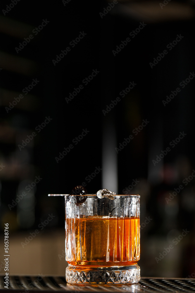 Old fashioned cocktail, consisting of Bourbon, Angostura Bitter, sugar cubes, a few drops of water, ice cubes, orange, maraschino cherry