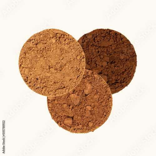 An alkalized cocoa powder. Comparison of dutch process cocoa with natural cocoa powder. Three piles of texture cocoa powder of different colors on a beige background. Top view, square photo