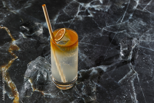 Dark n Stormy cocktail standing on the black marble background. Refreshing Boozy Rum Dark and Stormy Cocktail with Ginger Beer. photo