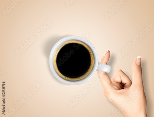 Female hand with white cup of coffee on pastel background